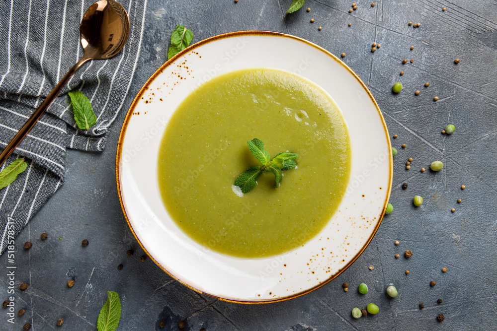 Cream of spinach soup with mint and peanut top view on grey table Cream of spinach soup with mint and peanut top view on grey table