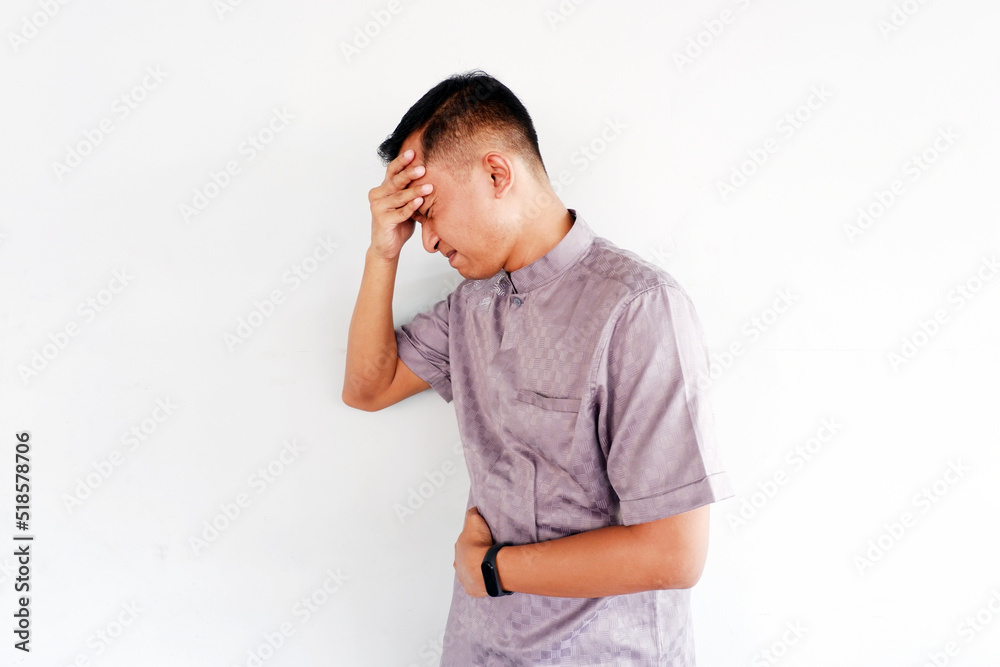 Asian young man holding his head with stress expression,headache and stomachache isolated on grey background Asian young man holding his head with stress expression,headache and stomachache isolated on grey background