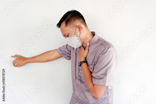 Asian man wearing a mask is holding the neck and experiencing shortness of breath. photo