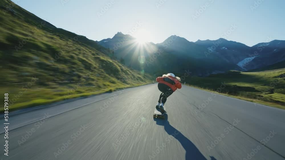 Cinematic downhill longboard session. Young woman skateboarding and making tricks between the curves on a mountain pass. Concept about extreme sports and people