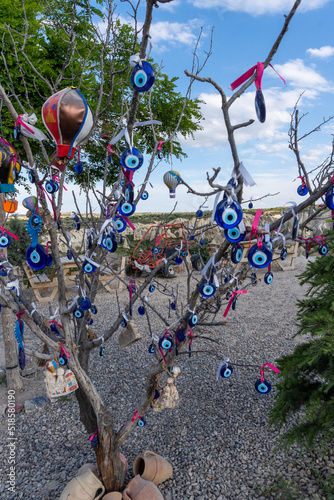 Tree decorated with Turkish beads, in the Valley of Love in Cappadocia, with a blue sky with white clouds.