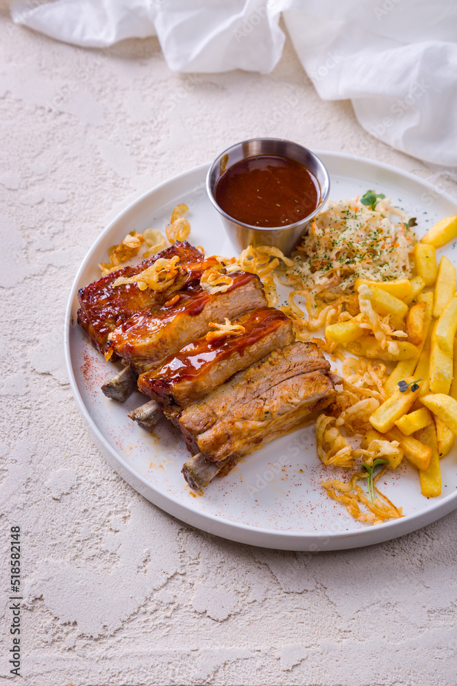Fried pork ribs in a sauce with French fries, mung bean salad, cabbage, fried onions and sauce Fried pork ribs in a sauce with French fries, mung bean salad, cabbage, fried onions and sauce