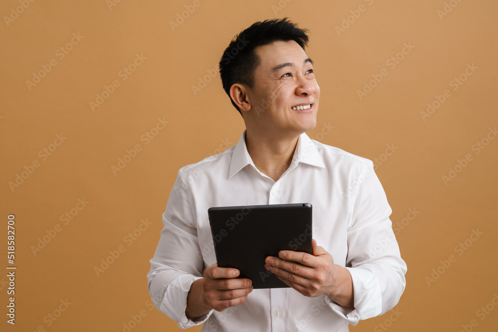 Asian mid man wearing shirt smiling while using tablet computer