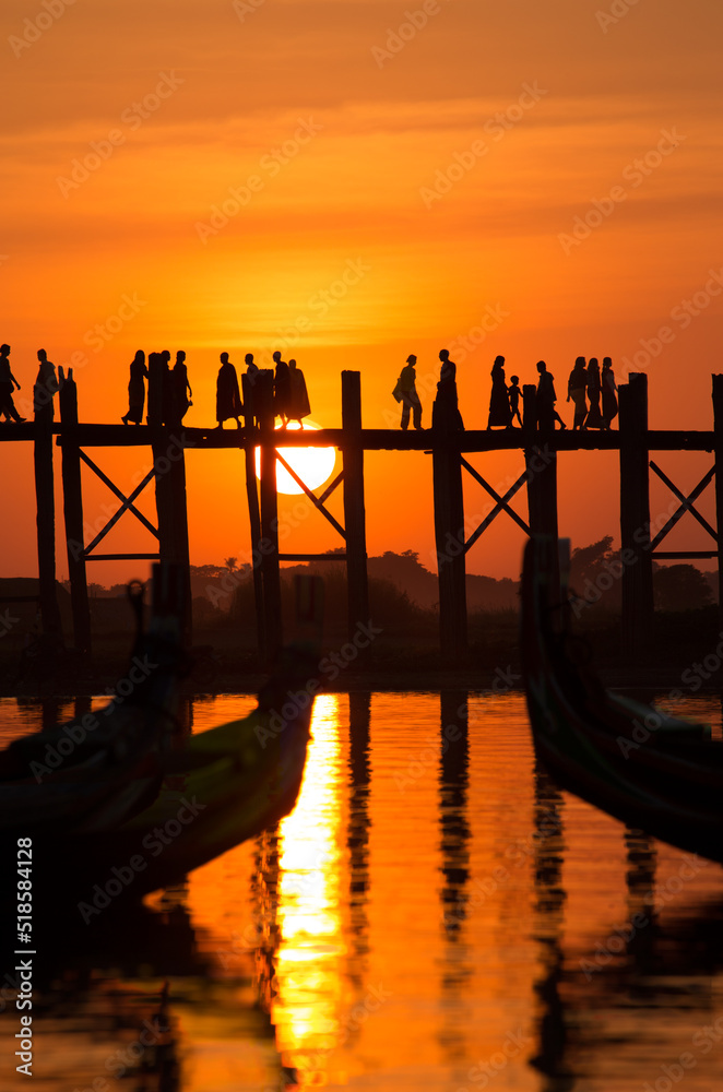 The people of Myanmar crossing U Bein Bridge at Sunset.