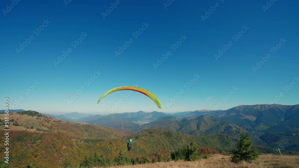 Paraglider taking off in the blue sky with mountain in background. Paraglider taking off in the blue sky with mountain in background.