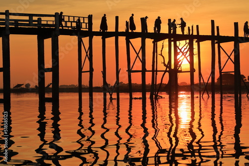 The people of Myanmar crossing U Bein Bridge at Sunset.