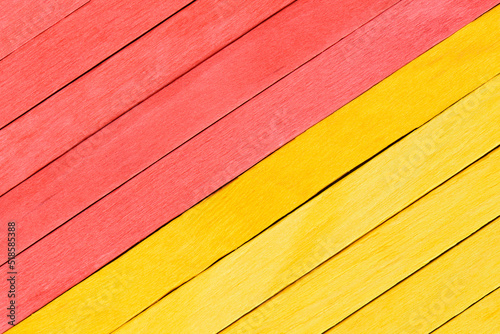 Bright yellow and red painted boards arranged diagonally. Wooden textured background. Textured straight planks in red and yellow.