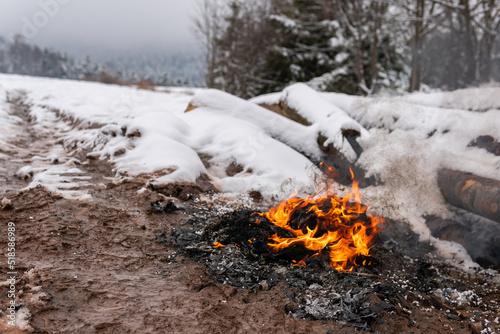 Garbage, trash, tree is on fire in the village in snowy weather