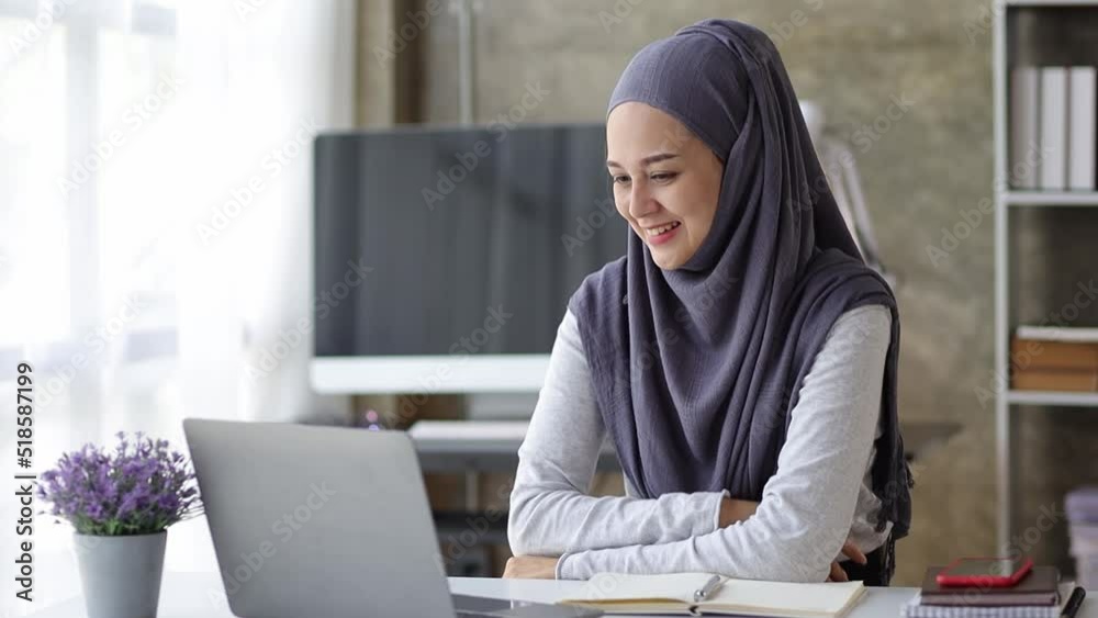 Muslim woman looking at laptop screen and remote video call with online dating, she talks to her friend through program on laptop. Concept of using communication technology. Muslim woman looking at laptop screen and remote video call with online dating, she talks to her friend through program on laptop. Concept of using communication technology.