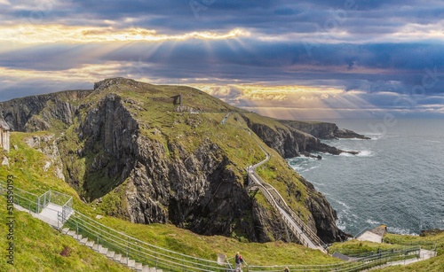 Shot of Mizen Head Bridge in Ireland against dramatic sky with sun rays daytime photo