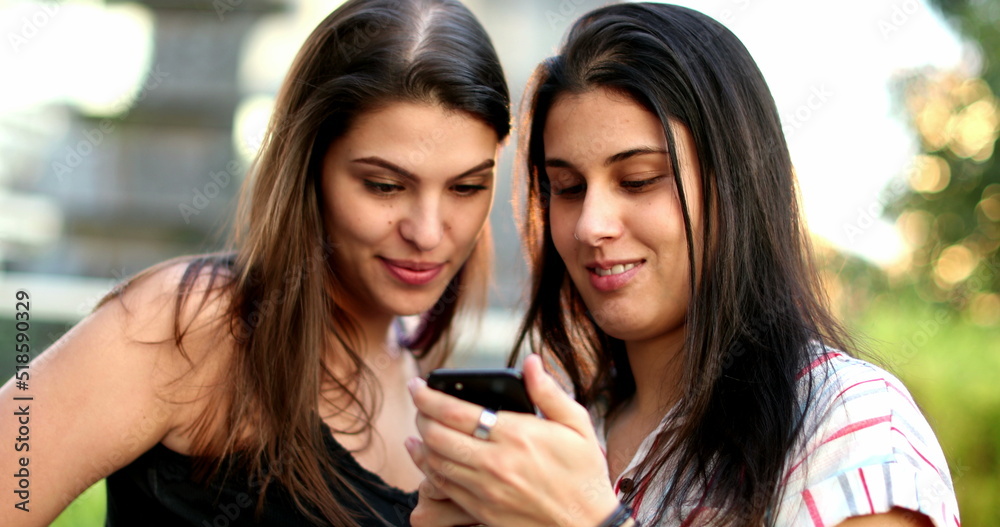 Women using smartphone outside. Female friends checking cellphone screen Women using smartphone outside. Female friends checking cellphone screen