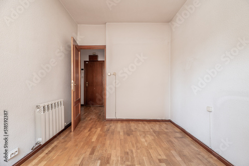 Empty room with oak wood floor  white painted walls and matching woodwork  aluminum radiator and sockets