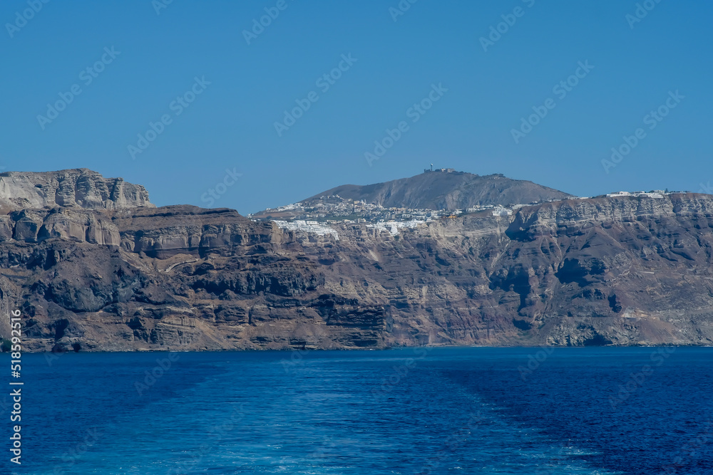 View of Santorini island and wave trails of a floating ferry boat