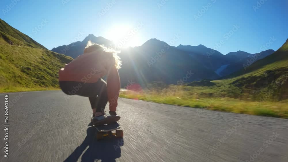 Cinematic downhill longboard session. Young woman skateboarding and making tricks between the curves on a mountain pass. Concept about extreme sports and people