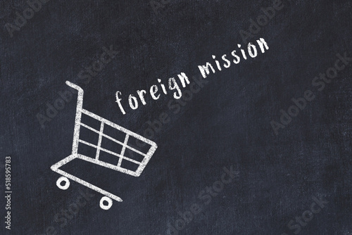 Chalk drawing of shopping cart and word foreign mission on black chalboard. Concept of globalization and mass consuming