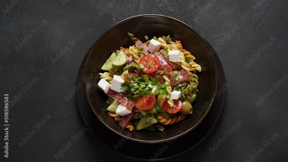 Italian pasta salad cucumbers, cherry tomatoes, olives, red onion,  salami, feta cheese, and Rotini