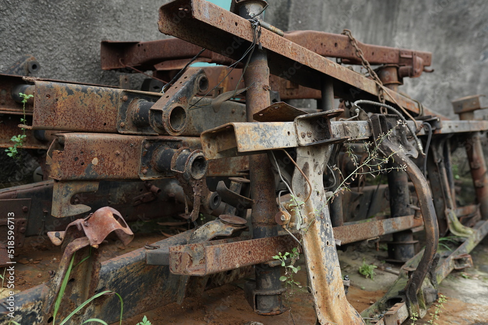 a collection of broken metal truck chassis for sale at a junk metal shop