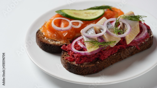 Danish open sandwich Smorrebrod on dark rye bread with herring, salmon, beetroot, red onions, and radish