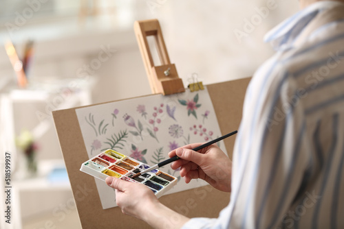 Woman painting flowers with watercolors in workshop, closeup