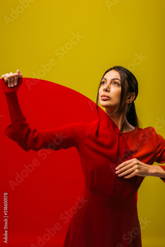 fashionable young woman in red dress holding round shape glass isolated on green.