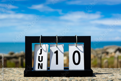 Jun 10 calendar date text on wooden frame with blurred background of ocean.