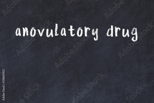 College chalk desk with the word anovulatory drug written on in photo