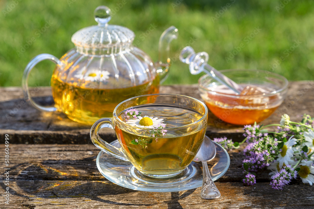 Herbal tea with chamomile and thyme in a transparent cup on an old wooden table on a sunny day Herbal tea with chamomile and thyme in a transparent cup on an old wooden table on a sunny day