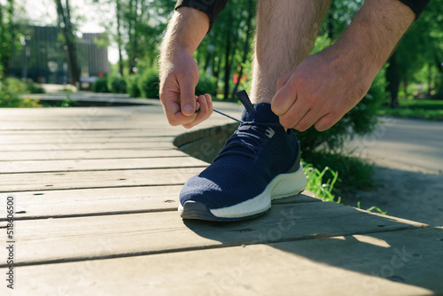 Man tying running shoes in the park outdoor