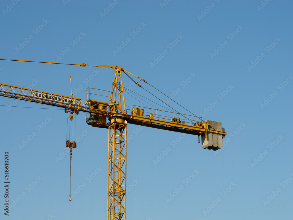 Close-up of a yellow tower crane  against a clear blue sky