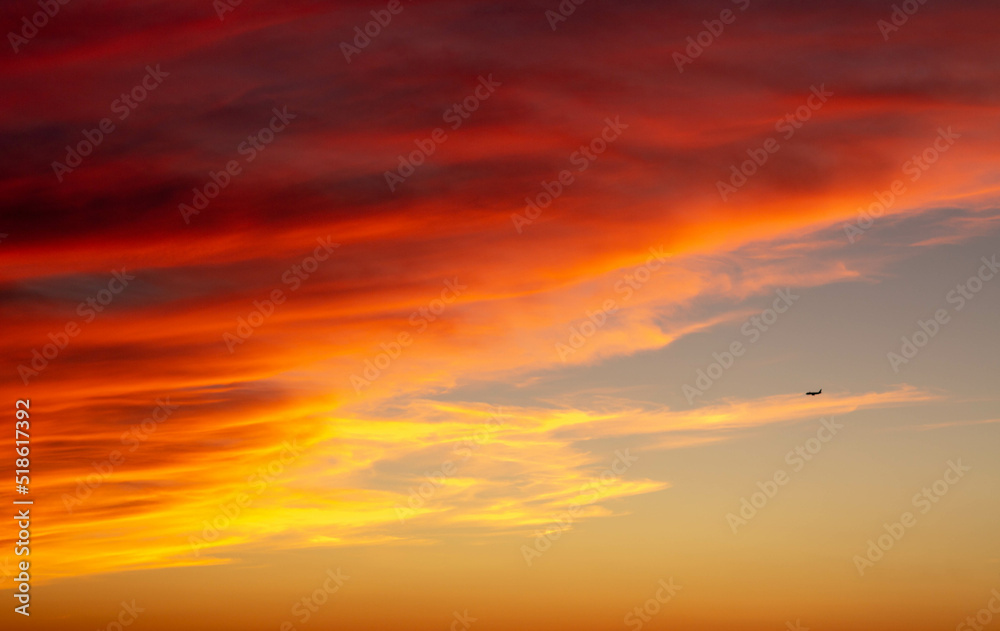  Abstract and cloudy sunset while an airplane flies by