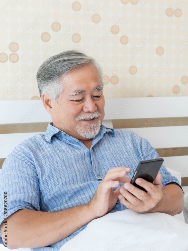 Senior Male , Asian old man using a smartphone feel happy good health on bed at home - lifestyle senior concept Senior Male , Asian old man using a smartphone feel happy good health on bed at home - lifestyle senior concept