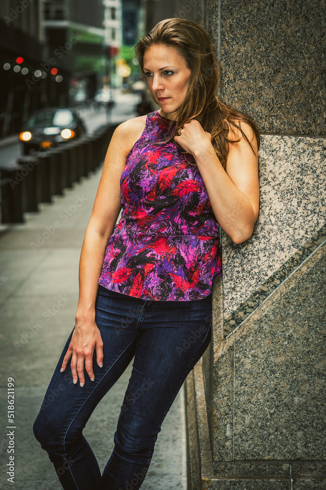 Thinking Outside. Young woman with damp hair, wearing purple pattern top, blue jeans, leaning against column on street in New York City, into deeply thinking..