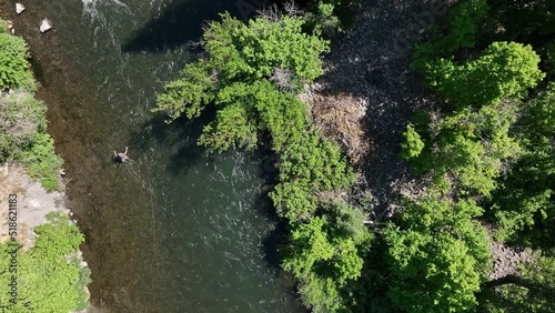Aerial view looking down at the Provo River with person fly fishing as they cast their line.