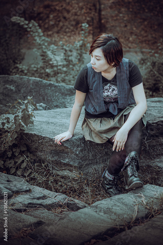 Obraz na płótnie Alone. Young Chinese Girl wearing sleeveless long blouse with black T shirt, black leggings and boots, sitting on rocks, looking around, thinking. Black and White Photography. w salonie