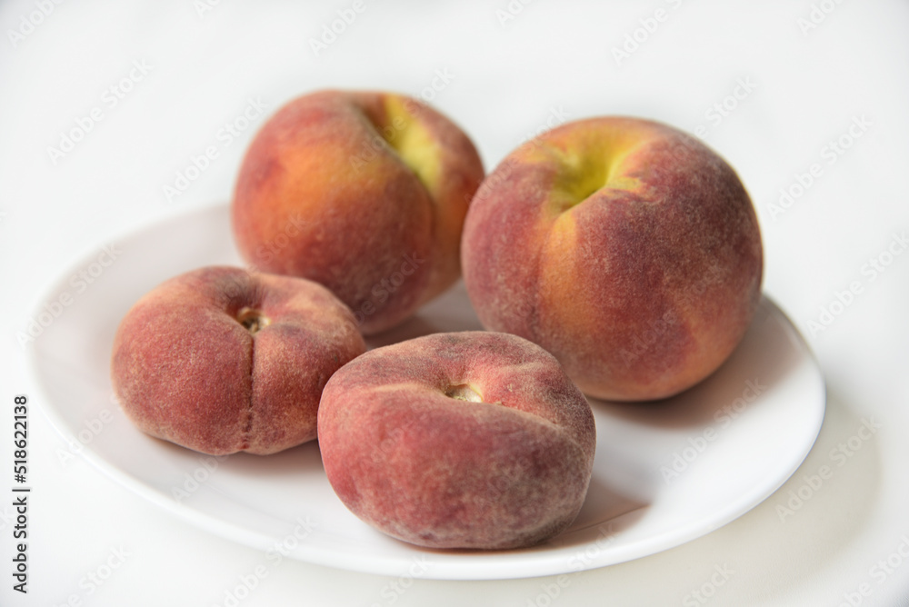Juicy red and yellow peaches on a white plate. Delicious peaches for lunch.