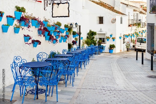 Fototapet Row of blue cafe tables and chairs with potted plants in the town of Mijas, Pueb