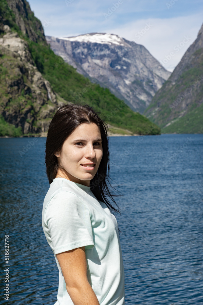 Young tourist girl in the foreground and behind her the fjord with the high mountains in Gudvangen - Norway Young tourist girl in the foreground and behind her the fjord with the high mountains in Gudvangen - Norway