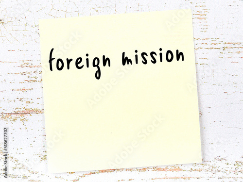 Yellow sticky note on wooden wall with handwritten word foreign mission