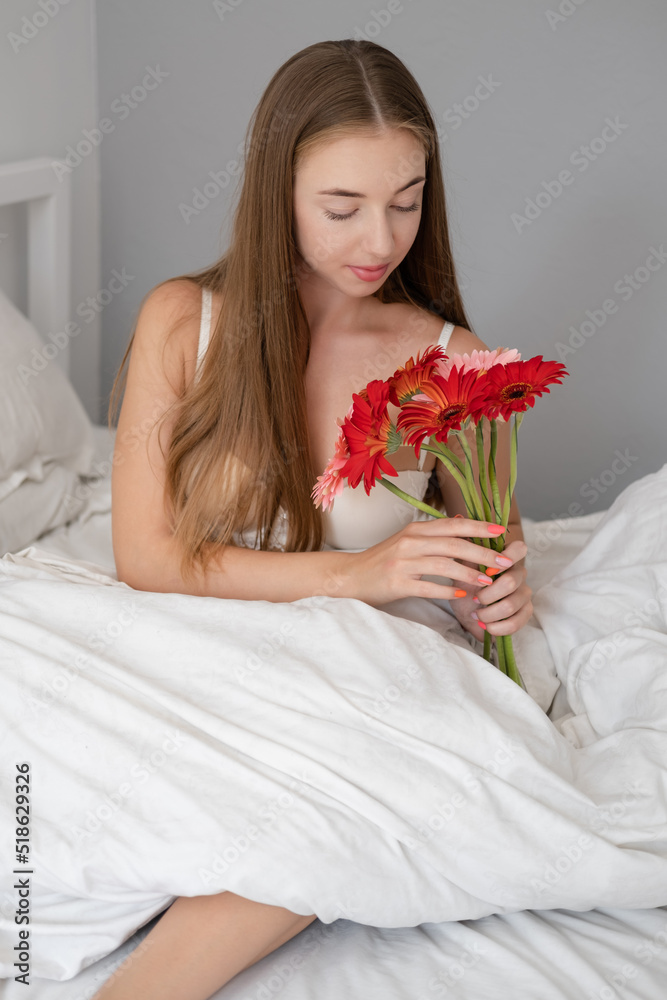charming girl with bouquet of flowers in white bedroom. relaxation, calmness charming girl with bouquet of flowers in white bedroom. relaxation, calmness