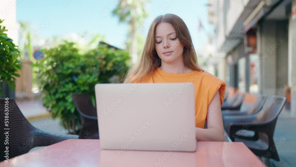 Young woman using laptop sitting on table at coffee shop terrace Young woman using laptop sitting on table at coffee shop terrace