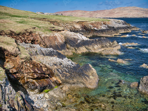 Dramatic coastal cliff scenery on the Ness of Hillswick, Northmavine, in the UNESCO Global Geopark of Shetland, UK - taken on a sunny day showing the clear, blue water of the Islands in the North Sea. photo