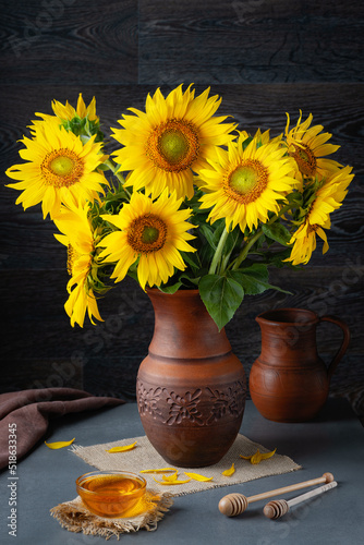 Still life with bouquet of sunflowers and honey on a grey table