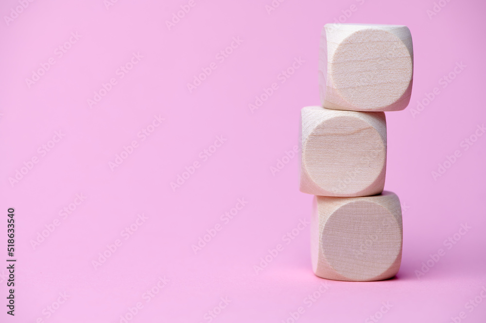 three wooden cubes on each other, copy space for any text, pink background paper