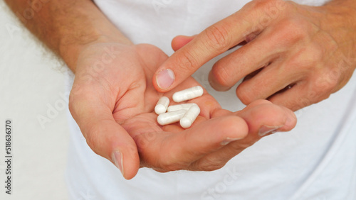 Close-up of a man's hand holding medicine capsules and about to take them