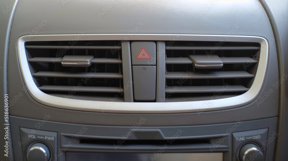 Air conditioning on the dashboard of the car flanks the red triangle sign which functions to turn on the hazard lights. Air conditioning on the dashboard of the car flanks the red triangle sign which functions to turn on the hazard lights.