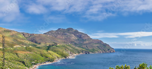 Photo A landscape of a mountainside with an ocean view and blue sky background with a lush, green botanical garden or national park