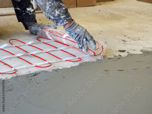 Fotografía a worker unfolds a roll of warm electric floor for laying under a cement screed
