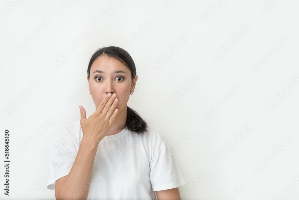 asian girl surprised with open mouth. young asian woman in a white t-shirt on a white background is confused and surprised, covering her mouth with her hands asian girl surprised with open mouth. young asian woman in a white t-shirt on a white background is confused and surprised, covering her mouth with her hands