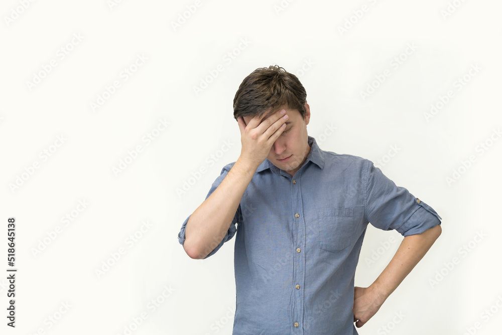 young attractive man in a blue shirt on a white background holds his head, the concept of a problem and a difficult task, business. predicament fear and confusion young attractive man in a blue shirt on a white background holds his head, the concept of a problem and a difficult task, business. predicament fear and confusion