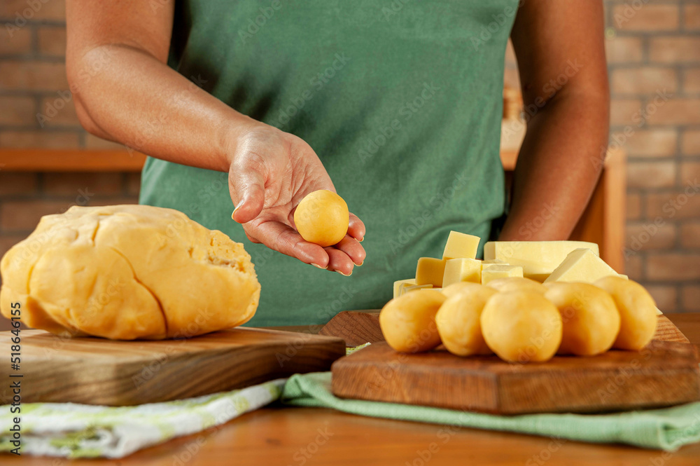 Woman holding brazilian cheese stuffed croquette (bolinha de queijo) on a wooden table. Woman holding brazilian cheese stuffed croquette (bolinha de queijo) on a wooden table.